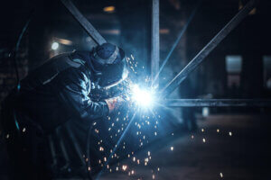 Homem soldando uma estrutura métalica em uma fábrica